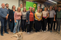Die gewählten Grünen Listenkandidat:innen stehen nebeneinander vor einem Grünen Rollup. Im Vordergrund eine Hündin.