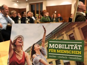Flyer Mobilität und im Hintergrund gefülltes Bürgerstüberl
