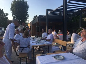 in weiß gekleidete Menschen sitzen in der Dämmerung an Tischen