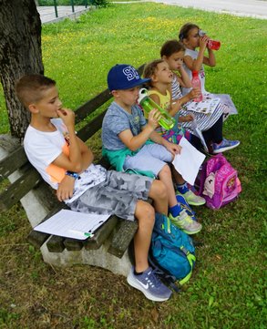 Kinder machen auf einer Bank an einem Baum Pause