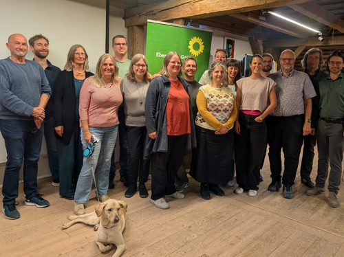 gewählte Listenkandidat:innen des OV Ebersberg Die gewählten Grünen Listenkandidat:innen stehen nebeneinander vor einem Grünen Rollup. Im Vordergrund eine Hündin.