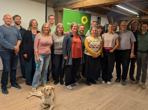 gewählte Listenkandidat:innen des OV Ebersberg Die gewählten Grünen Listenkandidat:innen stehen nebeneinander vor einem Grünen Rollup. Im Vordergrund eine Hündin.