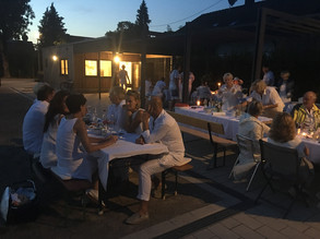 in weiß gekleidete Menschen sitzen am Abend an Tischen 