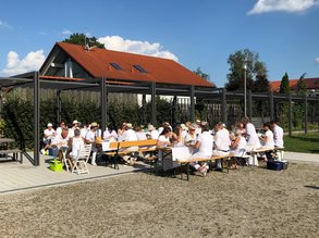 Dorfplatz mit Blick auf die Gäste an weißen Tischen
