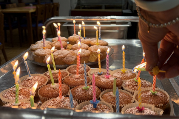 Zwei Tablets mit Cupcakes auf denen angezündete Kerzen sind